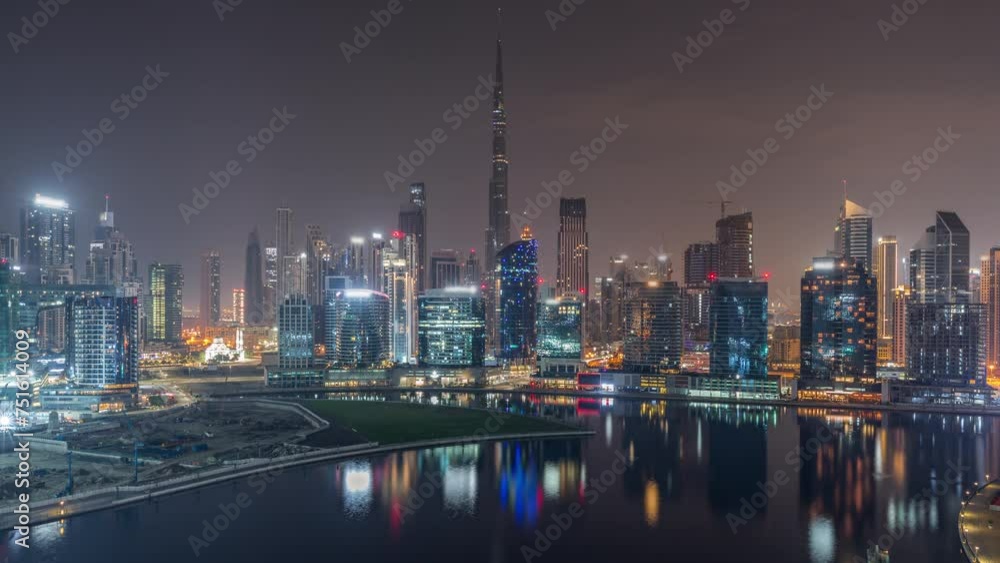 Aerial view to Dubai Business Bay and Downtown during all night with the various skyscrapers and towers along waterfront on canal night timelapse. Construction site with cranes Aerial view to Dubai Business Bay and Downtown during all night with the various skyscrapers and towers along waterfront on canal night timelapse. Construction site with cranes