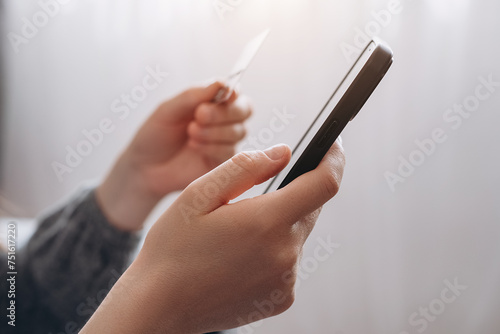 Close up of female hands holding credit card and smartphone, unknown girl paying online, using banking service, entering information, shopping, ordering in internet store, doing secure payment