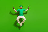 Full length photo of overjoyed person jumping arms hold beer bottle isolated on green color background