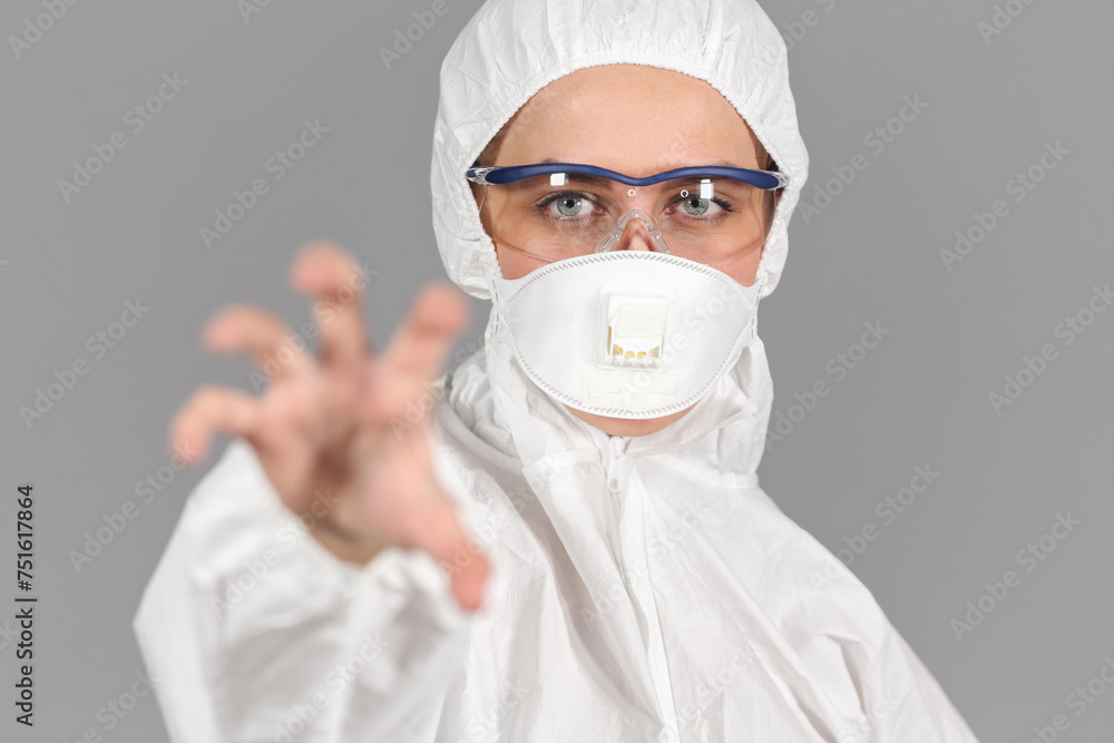 Half-growth portrait of woman in white protective suit of synthetic paper, looking at us, making hand gesture, on gray background Half-growth portrait of woman in white protective suit of synthetic paper, looking at us, making hand gesture, on gray background