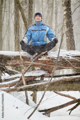 Εκτύπωση καμβά Man sits on fallen trunk in forest meditating during snowfall on winter day