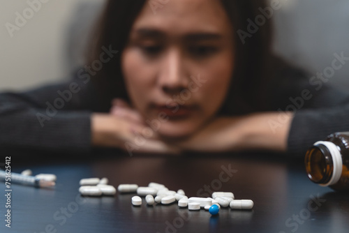 Anti drug, drug addict asian young woman, girl hand reaching for syringe, medicament with narcotic on table at home, abuse overdose. Sick pain of health, unhealthy people. Suicide depressed or despair © Pormezz