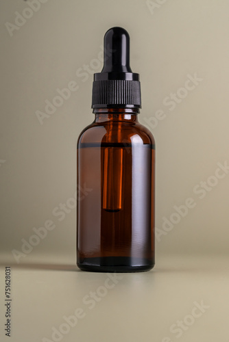 Dark brown glass bottle with dropper pipette with serum or essential oil on a beige background. Skincare cosmetic Beauty concept for face body care. Place for text.