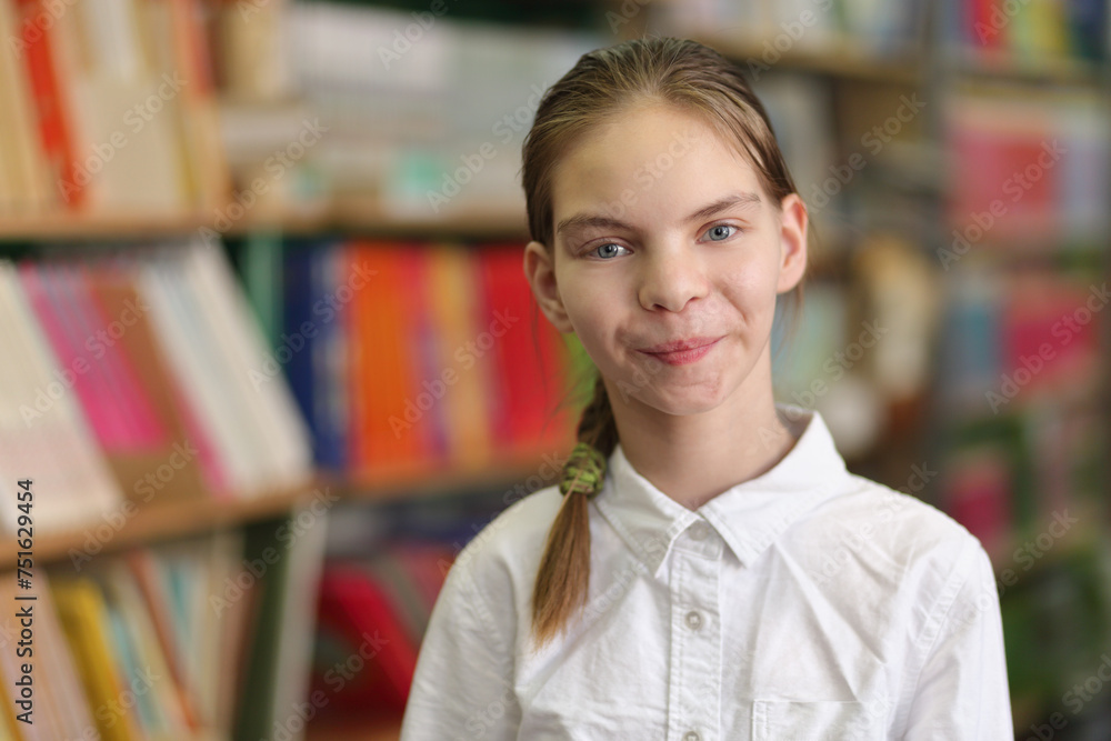 Half growth portrait of student in white shirt and ponitail, amid shelves of books, looking at camera and smile Half growth portrait of student in white shirt and ponitail, amid shelves of books, looking at camera and smile