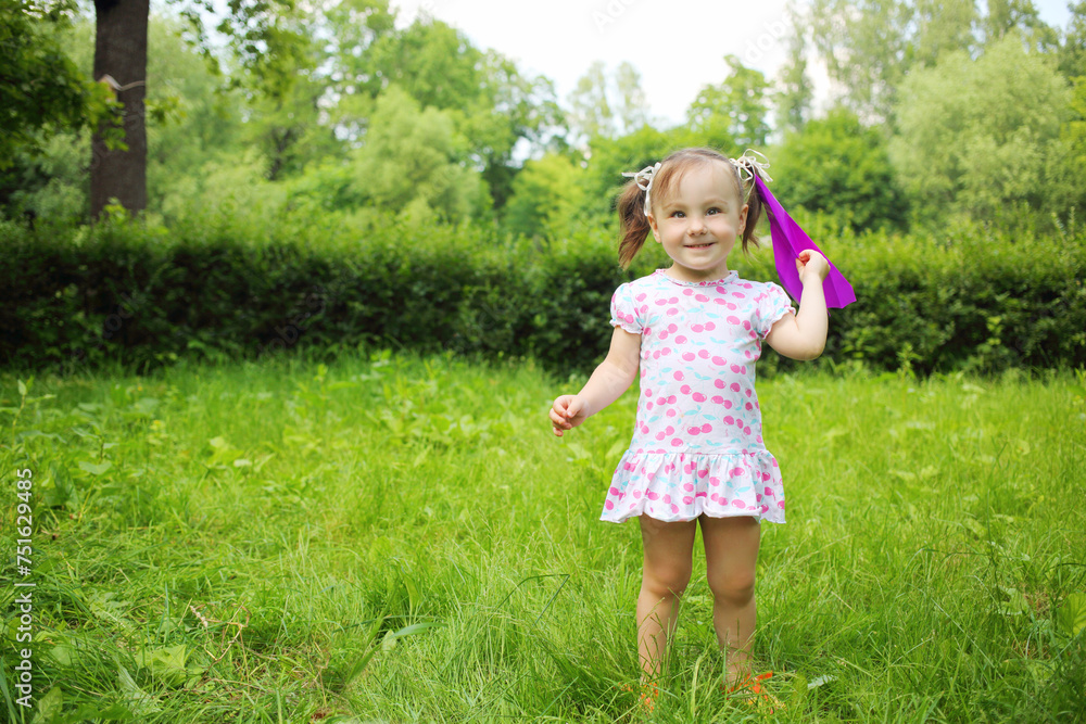 Little cute happy girl throws paper airplane in summer park Little cute happy girl throws paper airplane in summer park