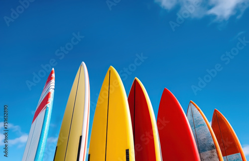 Set of differently colored surfboards stacked by the ocean photo