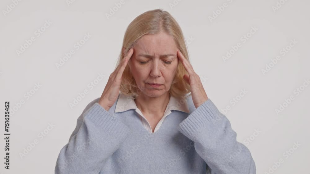 A woman is wincing in pain, holding her head with her arm due to a headache A woman is wincing in pain, holding her head with her arm due to a headache