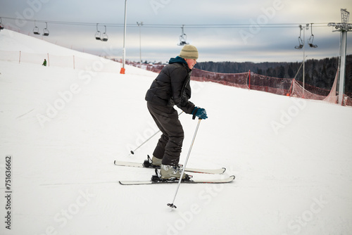 Teenage boy skis on snowy slope at ski resort photo