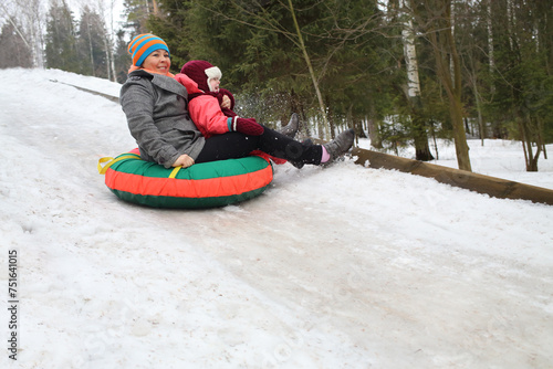 Woman with child rolling hills on a sledge in the forest