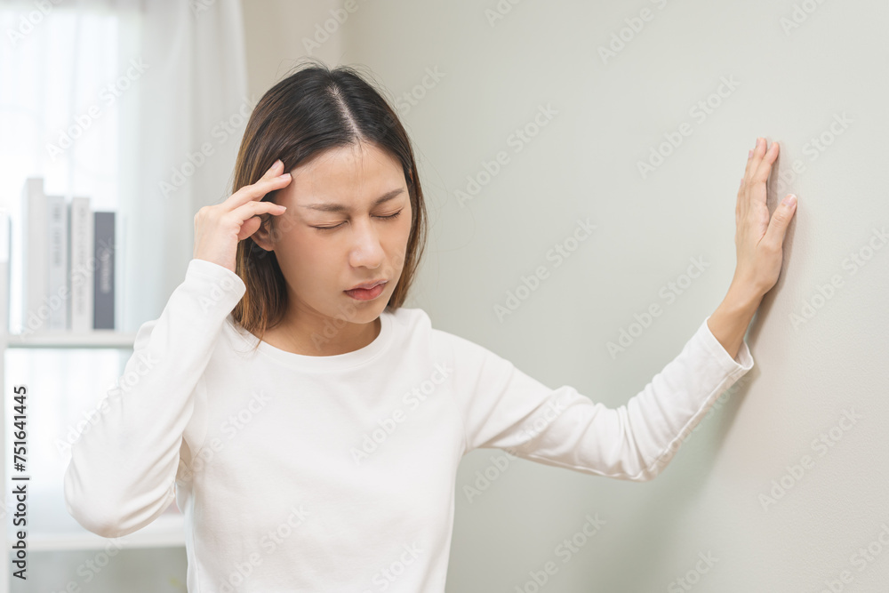 Dizzy asian young woman, girl headache or migraine pain. suffering from vertigo, difficulty standing up leaning on wall at home, holding head with hand, health problem of brain, inner ear not balance. Dizzy asian young woman, girl headache or migraine pain. suffering from vertigo, difficulty standing up leaning on wall at home, holding head with hand, health problem of brain, inner ear not balance.
