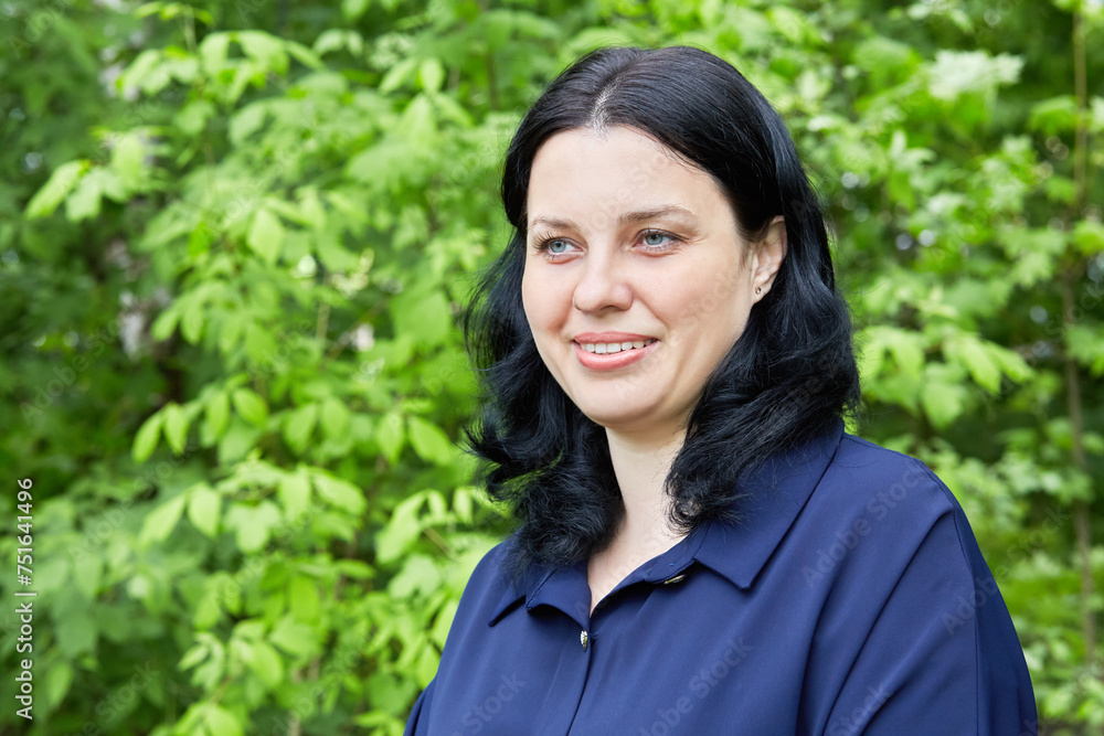 Humeral portrait of dark-haired smiling woman in green summer park Humeral portrait of dark-haired smiling woman in green summer park