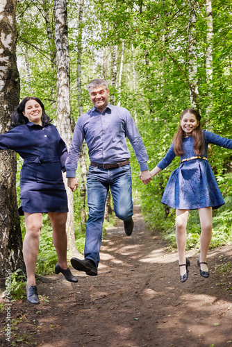 Happy family of three walks jumping in summer park © Pavel Losevsky