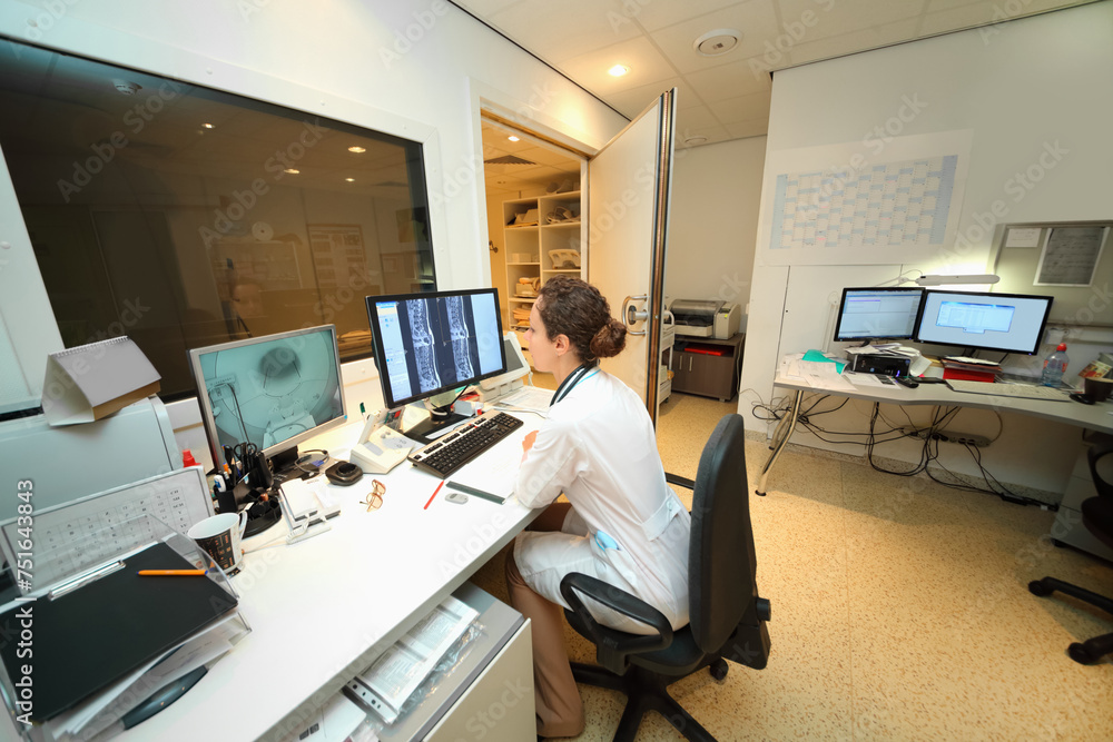 Experienced doctor looking at MRI scan of lumbar region on Monitor in control room Experienced doctor looking at MRI scan of lumbar region on Monitor in control room