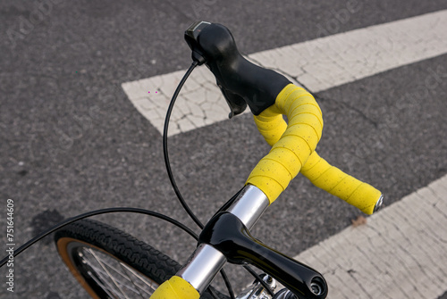 bike handlebar detail with bright yellow bar tape (bicycle cockpit, cycling) integrated shifters, brifters, black quill threaded stem, headset, titanium frame, silver aluminum bars, exposed cables photo