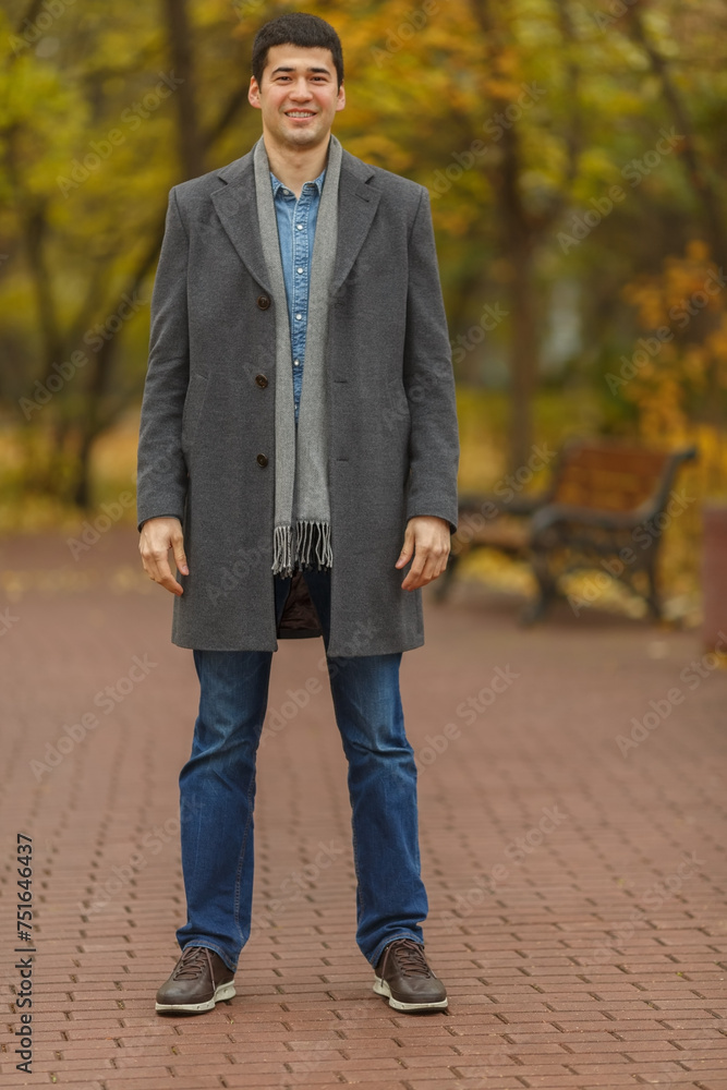 Portrait in full growth young man in gray coat in autumn park Portrait in full growth young man in gray coat in autumn park