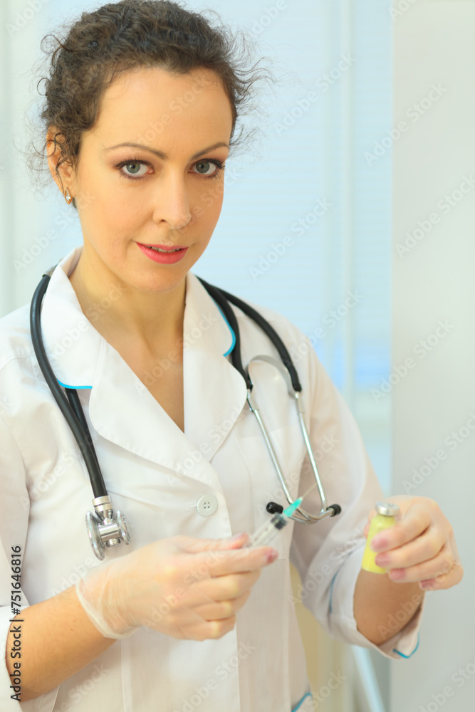 Health worker holding syringe and vial of medicine in her hands, standing in exam room Health worker holding syringe and vial of medicine in her hands, standing in exam room