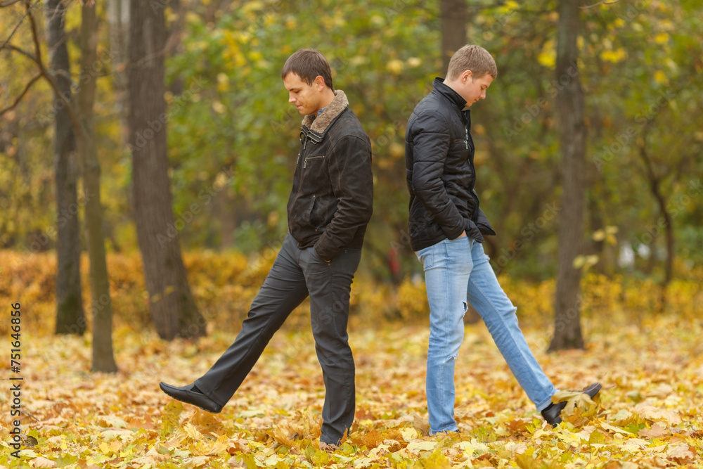 Full portrait of two friends walking in autumn park, under feet of yellow foliage Full portrait of two friends walking in autumn park, under feet of yellow foliage