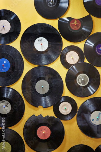 Old dusty damaged vinyl disks pinned tothe yellow wall photo