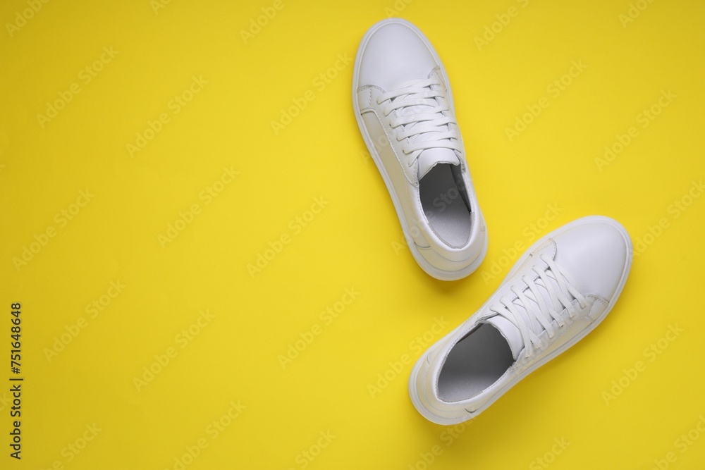 Pair of stylish white sneakers on yellow background, top view. Space for text Pair of stylish white sneakers on yellow background, top view. Space for text