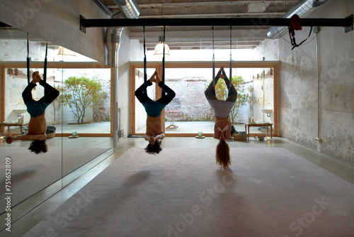 Unrecognizable man and woman performing aerial yoga