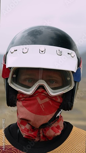 The face of adventure is captured in this close-up of a motorcyclist, his eyes shielded by goggles, and his face wrapped in a vibrant bandana. A classic black helmet with visor clips secures the look photo