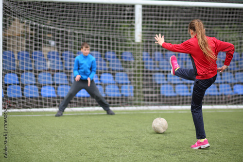 Girl in a red tracksuit throws the ball into the goal with boy keeper © Pavel Losevsky