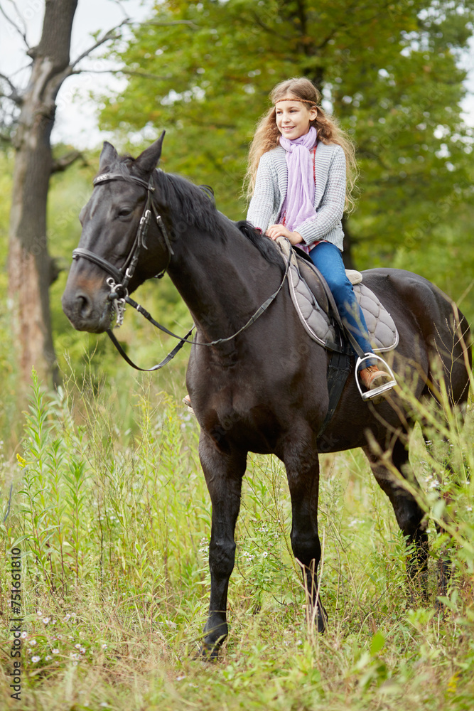 Teenage girl sits on chestnut horse in the park Teenage girl sits on chestnut horse in the park