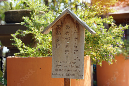 Japanese style wooden sign with messages written in Japanese. English and Thai, which is translated as written: let things go if you want to find peace in your mind, to give ideas to readers. photo