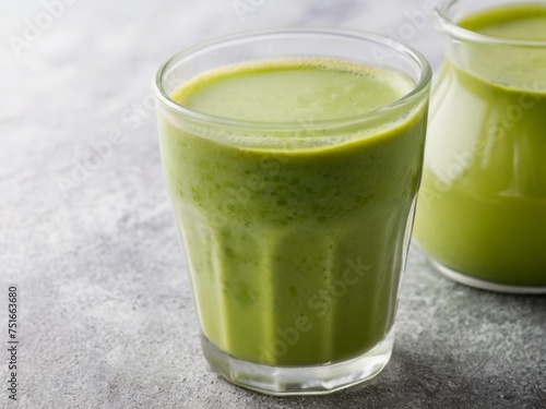 Green smoothie with spinach or avocado in a glass on a grey background