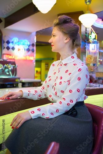 Profile of beautiful girl in blouse with red lips at the bar wit photo