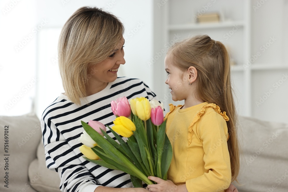 Little daughter congratulating her mom with bouquet of beautiful tulips at home. Happy Mother's Day Little daughter congratulating her mom with bouquet of beautiful tulips at home. Happy Mother's Day