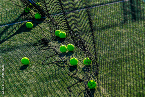 Bright tennis balls on green court, caught in the net