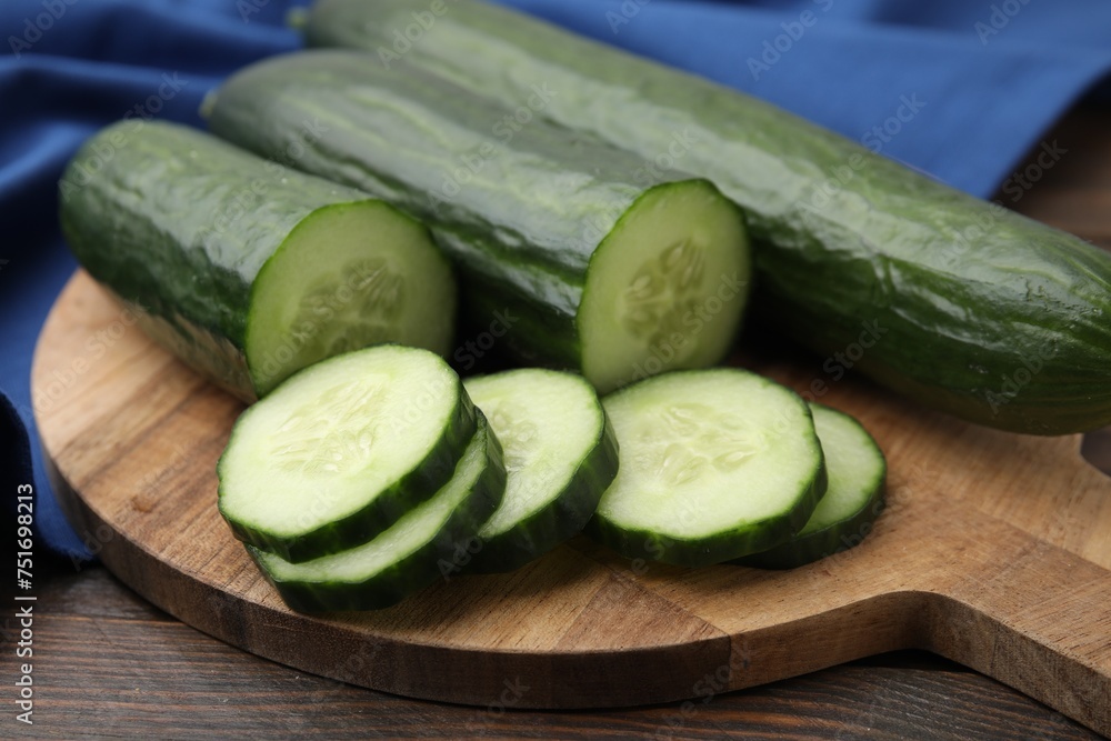 Fresh whole and cut cucumbers on wooden table, closeup - obrazy, fototapety, plakaty 