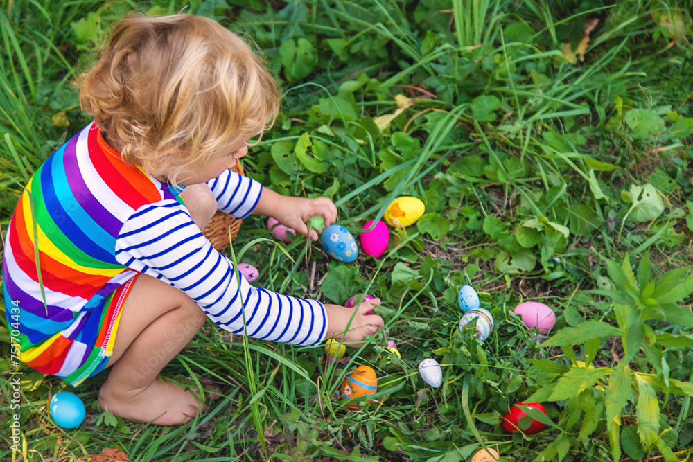 A child collects Easter eggs in the grass. Selective focus. A child collects Easter eggs in the grass. Selective focus.