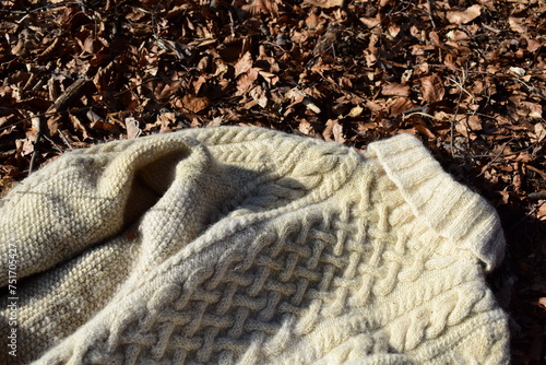 Pullover mit Zopfmuster in naturweißer Schafwolle als Hintergrund