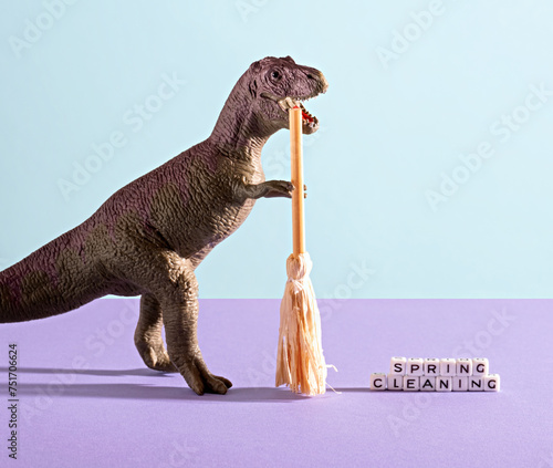 Dinosaur sweeps cubes with the words spring cleaning