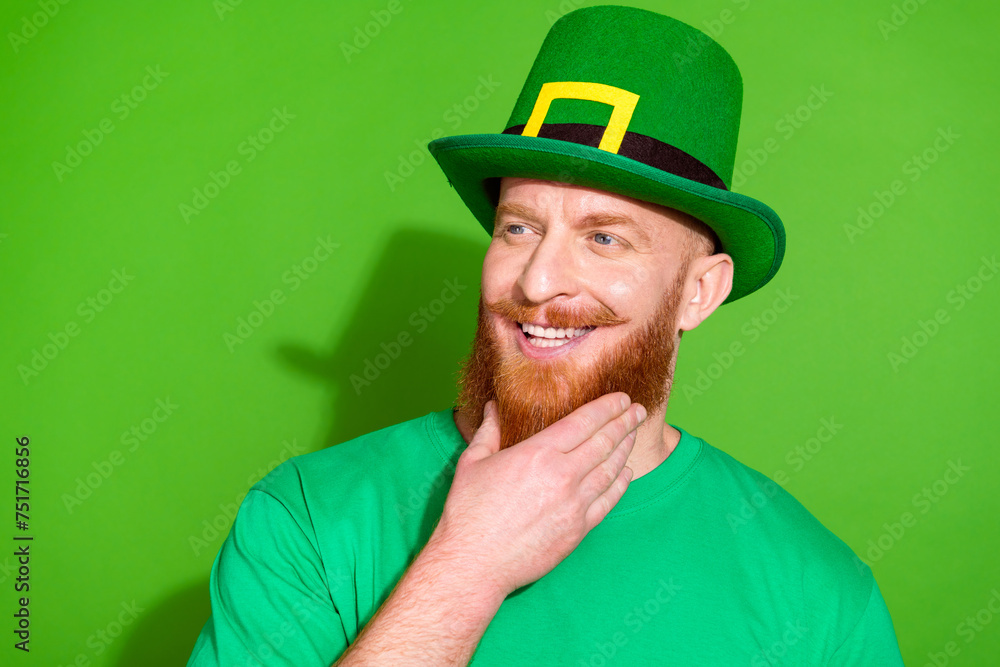 Photo of cool funky young man hand touch chin beard look empty space isolated on green color background Photo of cool funky young man hand touch chin beard look empty space isolated on green color background