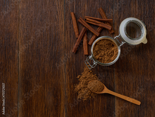 cinnamon sticks and cinnamon powder on a brown wooden table, top view.