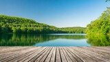 empty wooden deck with a blurred background of a peaceful lake and lush green forest under a clear sky