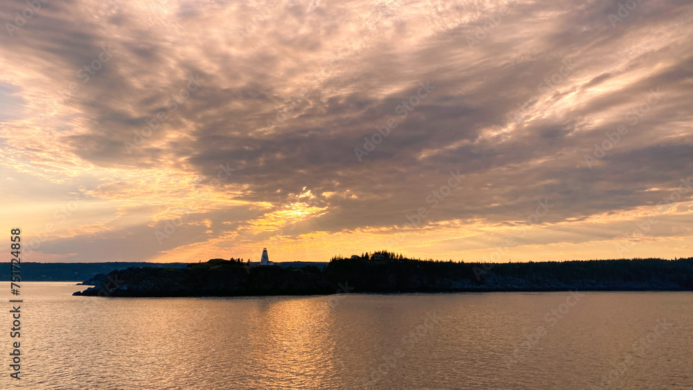 Orange sunset sky over island with lighthouse