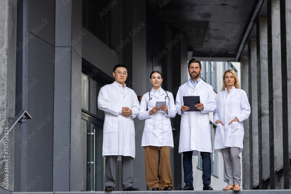 Four medical professionals in lab coats stand confidently on hospital steps, portraying teamwork and expertise. Four medical professionals in lab coats stand confidently on hospital steps, portraying teamwork and expertise.