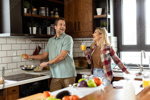 Man and woman sharing a laugh as they cook in a cozy, well-organized kitchen