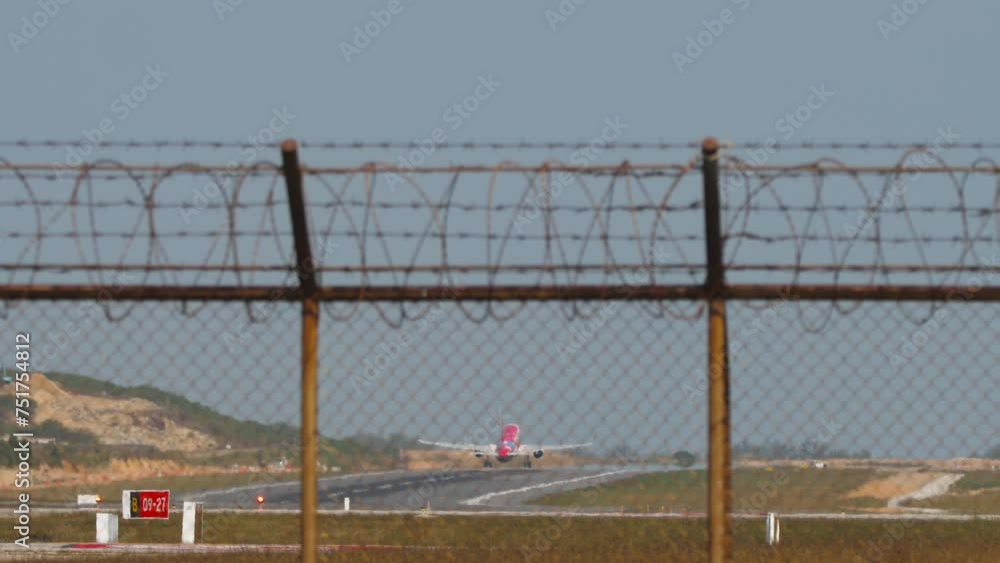 Jet airplane take off, long shot, rear view. Passenger flight departure. Panoramic view of the runway through the airport fence. Travel concept Jet airplane take off, long shot, rear view. Passenger flight departure. Panoramic view of the runway through the airport fence. Travel concept