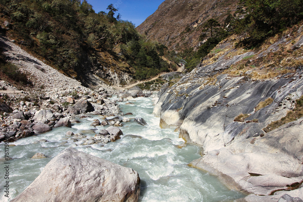 Fast moving rapids of the Dudh Kosi river originating from the Khumbu and Cho Oyu glaciers seen here in a scenic valley setting on the Everest Base Camp trek near Tengboche,Nepal - obrazy, fototapety, plakaty 