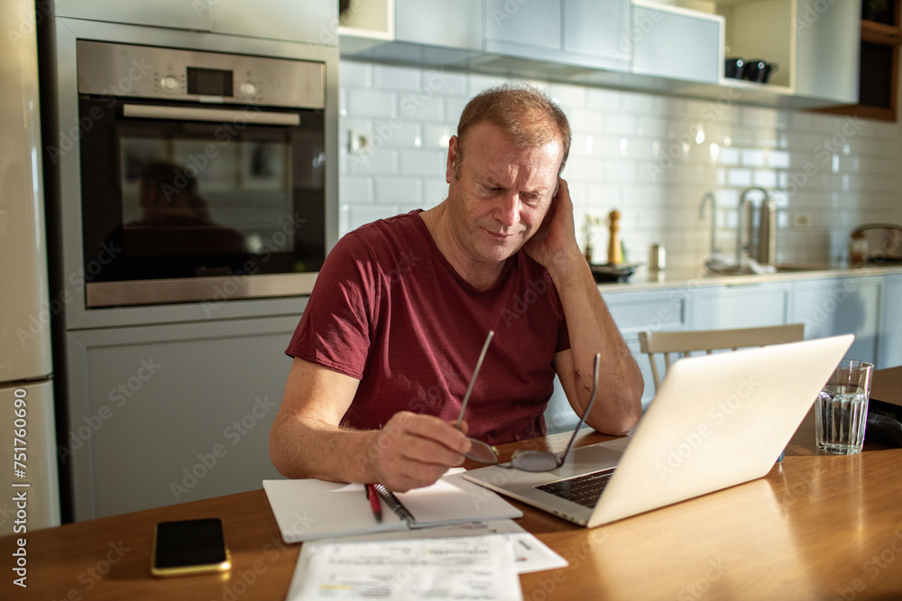 © Marko Geber - Stressed man going over bills at home