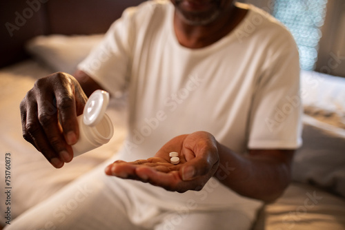 Senior man taking medication in bedroom photo