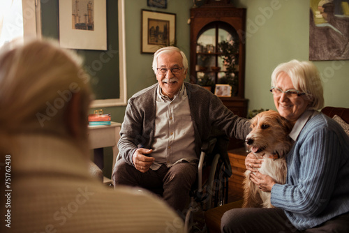 Happy senior couple with friends enjoying a conversation at home photo