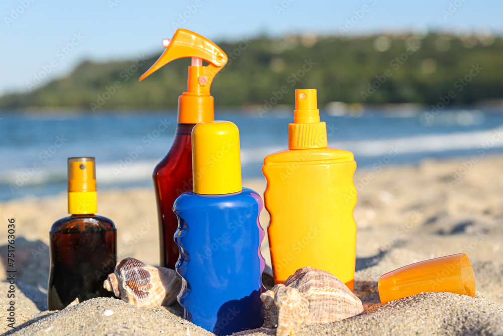Bottles of sunscreen cream with seashells on sand near ocean at beach Bottles of sunscreen cream with seashells on sand near ocean at beach