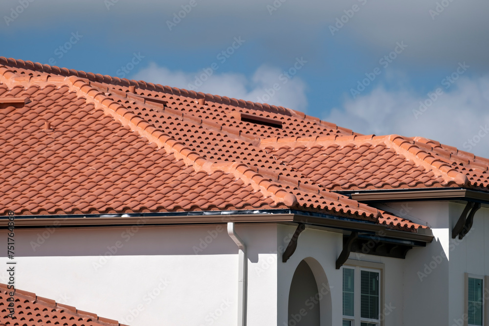 Overlapping rows of yellow ceramic roofing tiles covering residential building roof in southern Florida
