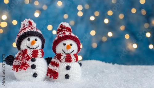 little knitted snowmen on the white snow on blue background © Kendrick